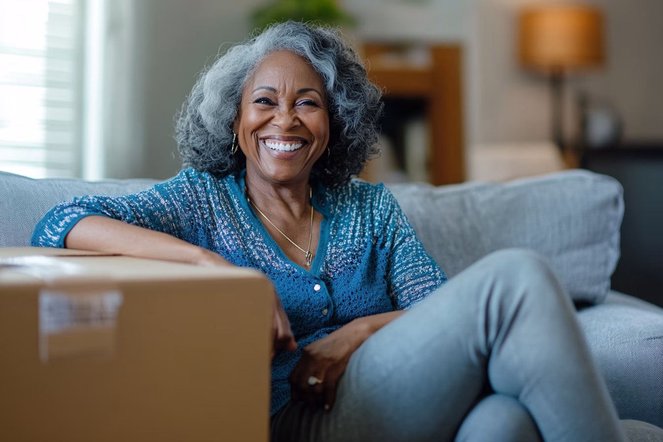 Smiling woman sitting on couch with package.