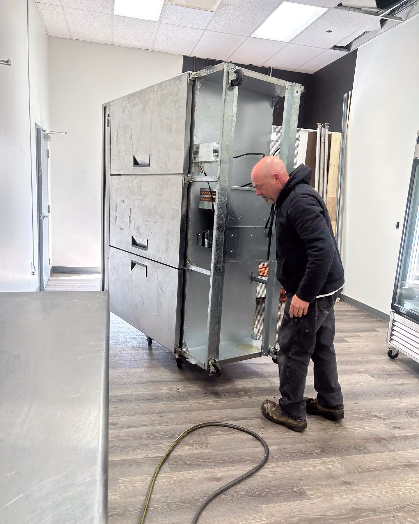 Man inspecting large industrial refrigerator unit indoors.