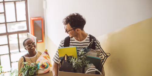 Moving into a college apartment carrying boxes up stairs in new home.